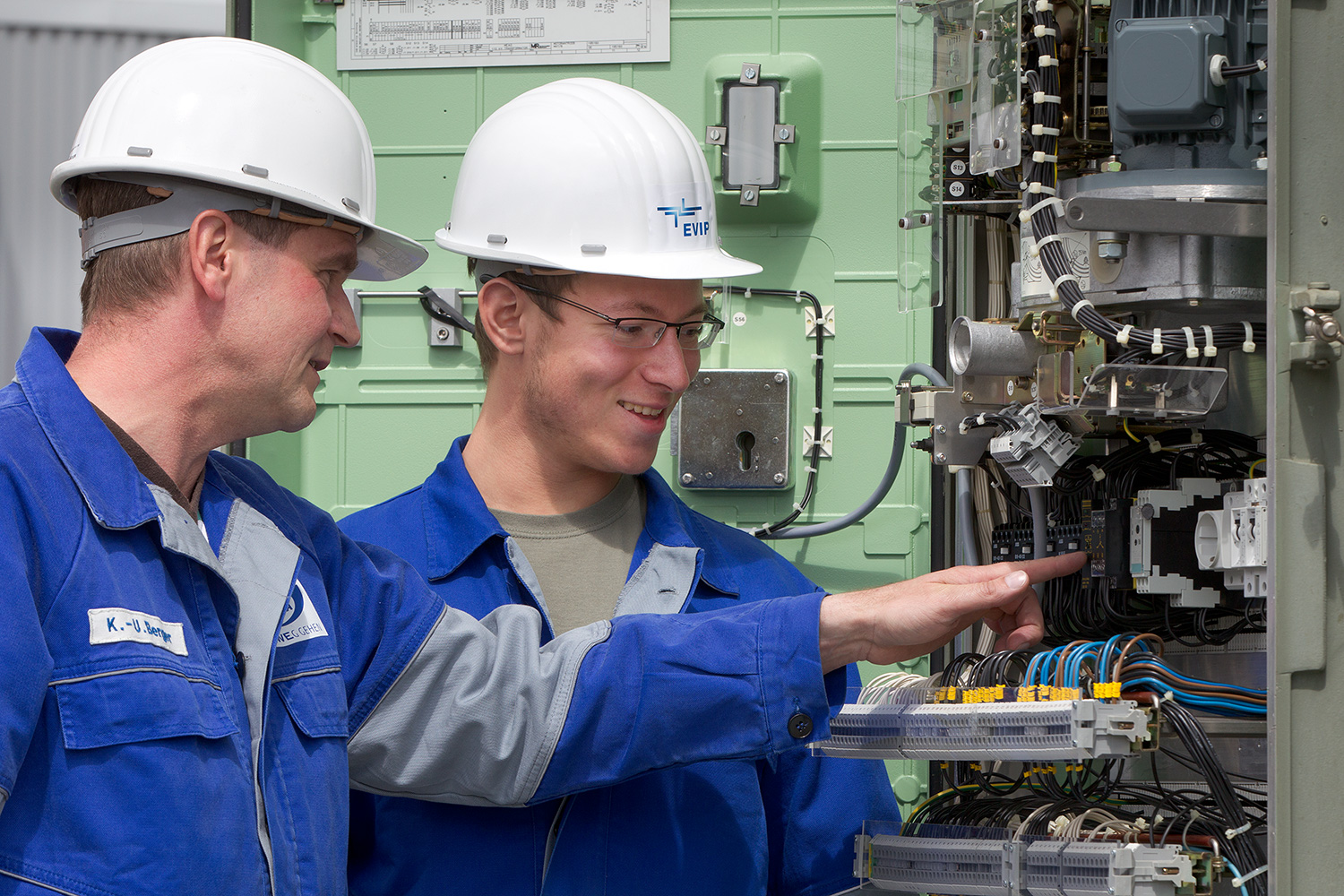 Zwei Mitarbeiter an einer Anlage mit vielen Kabeln