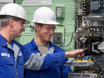 Zwei Mitarbeiter an einer Anlage mit vielen Kabeln Zwei Mitarbeiter an einer Anlage mit vielen Kabeln