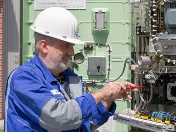 Mitarbeiter arbeitet mit einem Schraubenzieher an einer Anlage mit vielen Kabeln Mitarbeiter arbeitet mit einem Schraubenzieher an einer Anlage mit vielen Kabeln