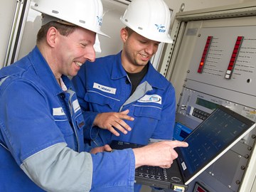 Zwei Mitarbeiter mit einem Laptop vor einer Anlage Zwei Mitarbeiter mit einem Laptop vor einer Anlage