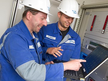 Zwei Mitarbeiter mit einem Laptop vor einer Anlage Zwei Mitarbeiter mit einem Laptop vor einer Anlage