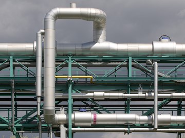 Große silbergraue Rohrleitungen an einem türkisfarbenen Stahlgerüst im Freien Große silbergraue Rohrleitungen an einem türkisfarbenen Stahlgerüst im Freien