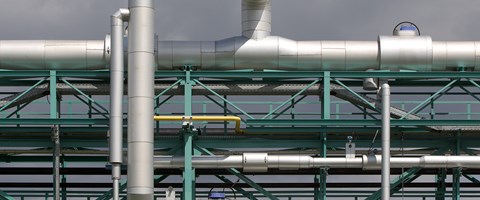 Große silbergraue Rohrleitungen an einem türkisfarbenen Stahlgerüst im Freien Große silbergraue Rohrleitungen an einem türkisfarbenen Stahlgerüst im Freien