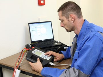 Techniker sitzt mit portable Eingabegerät und Laptop an einem Tisch Techniker sitzt mit portable Eingabegerät und Laptop an einem Tisch