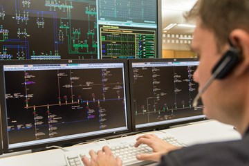 Mitarbeiter mit einem Headset vor mehreren Monitoren Mitarbeiter mit einem Headset vor mehreren Monitoren