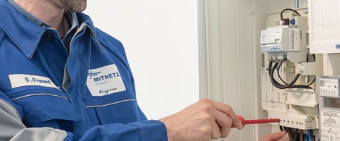 Mitarbeiter arbeitet mit einem Schraubenzieher an einem Stromzähler Mitarbeiter arbeitet mit einem Schraubenzieher an einem Stromzähler